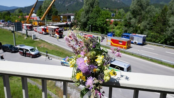 Blumen sind am zweiten Tag nach einem schweren Zugunglück an einer Brücke befestigt. Bei dem Unglück sind mindestens vier Menschen ums Leben gekommen. Ein Regionalexpress entgleiste in der beliebten oberbayerischen Urlaubsregion auf dem Weg von Garmisch nach München.