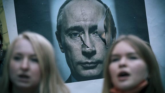 Ein Plakat von Wladimir Putin hinter zwei Frauen