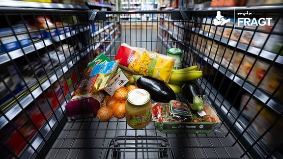 Verschiedene Lebensmittel liegen in einem Supermarkt in einem Einkaufswagen. 
