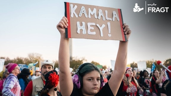 Ein Mädchen hält auf einer Demonstration ein Schild mit der Aufschrift "Kamala Hey" hoch.