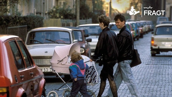 Eine junge Familie mit einem Kinderwagen überquert die Straße (1990)
