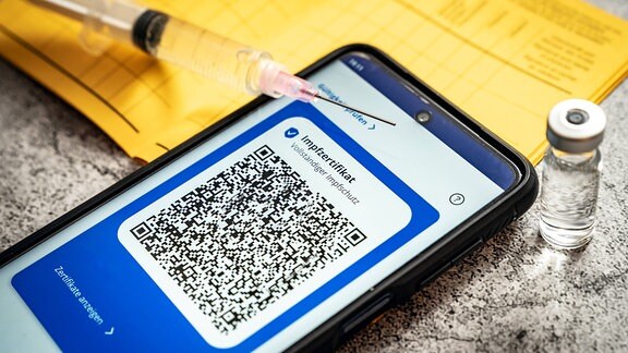 Digitaler Impfpass auf einem Smartphone-Display mit Impfbuch und Spritze
