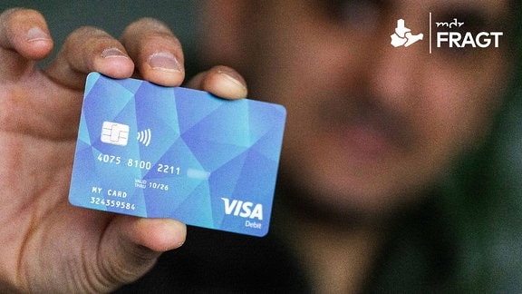 Ein Geflüchteter hält eine Debitcard in der Hand