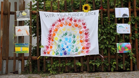 Kindermalereien und ein Banner mit der Aufschrift Wir Vermissen Euch hängen am Kinderhaus Pittiplatsch in Potsdam-Babelsberg