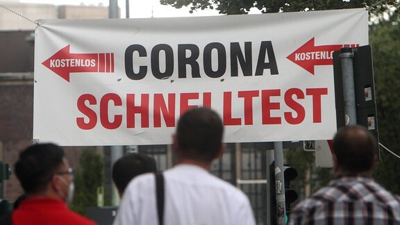 Menschen stehen vor einem Corona Testzentrum an.