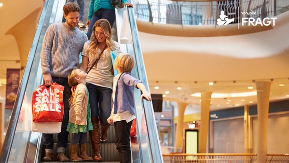 Eine Familie beim Einkaufsbummel auf einer Rolltreppe im Kaufhaus.
