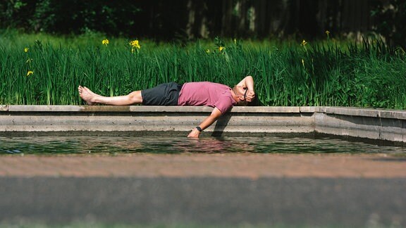 Mittagssonne Mann liegt im Park bei Wasser