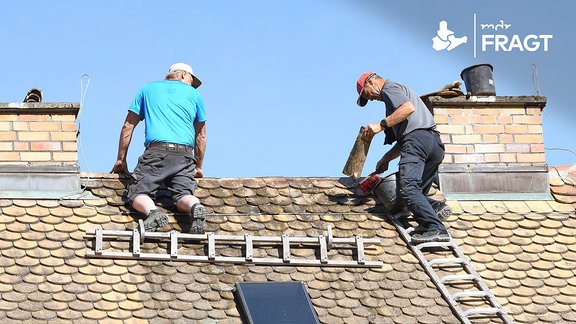 Dachdecker erneuern Schornsteine und Firstziegel auf dem steilen Dach eines Altbaus.