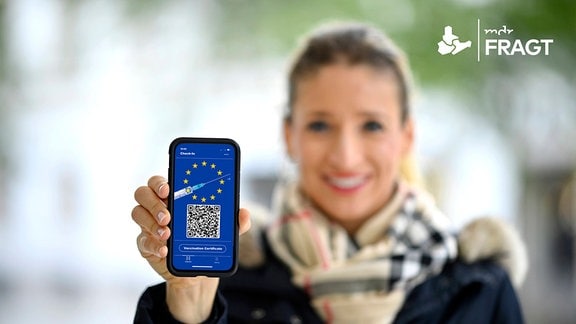 Frau zeigt Smartphone mit digitalem europäischen Impfpass mit QR-Code