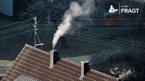 Weißer Dampf steigt bei eisigen Temperaturen aus einem Kamin eines Wohnhauses. 
