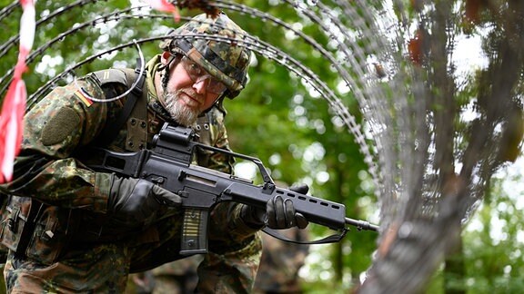 Soldat vor Stacheldraht mit Gewehr