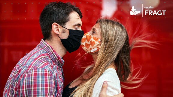 Mann und Frau mit Maske küssen sich