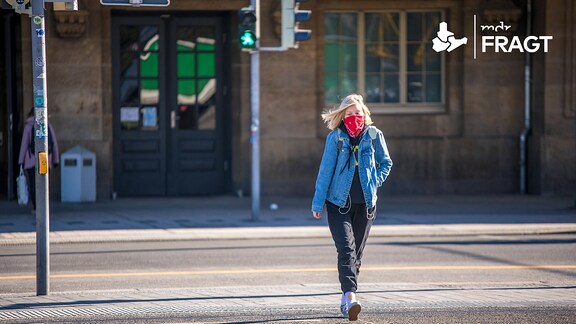 Eine Frau geht mit Mundschutz durch die Straßen