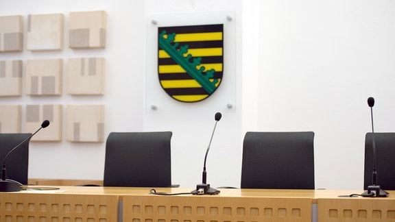 Ein Landeswappen des Freistaates Sachsen hängt in einem Gerichtssaal
