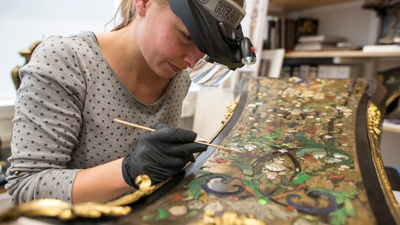 Ausstellung: eine Restauratorin bei der Arbeit mit dem Pinsel.