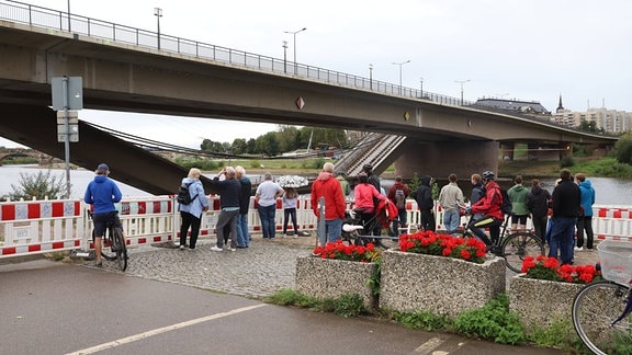 Schaulustige blicken auf die teilweise eingestürzte Carolabrücke.