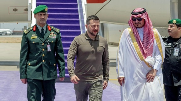 Wolodymyr Selenskyj (M), Präsident der Ukraine, wird vom stellvertretenden Gouverneur der Provinz Mekka, Prinz Badr bin Sultan bin Abdulaziz Al Saud, bei seiner Ankunft in Dschidda zur Teilnahme am 32. Gipfel der Arabischen Liga empfangen.