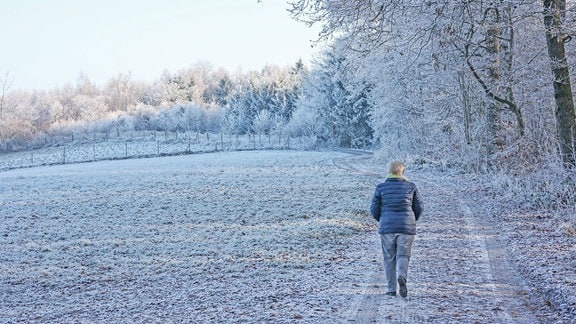 Eine Frau läuft durch eine Winterlandschaft.