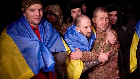 Auf diesem vom Pressebüro des ukrainischen Präsidenten zur Verfügung gestellten Foto tragen ukrainische Kriegsgefangene nach einem Gefangenenaustausch ukrainische Nationalfahnen.