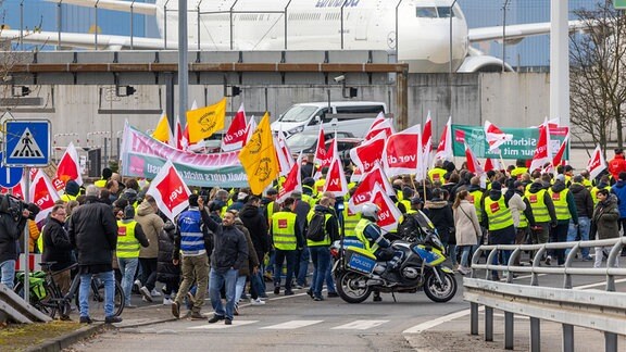 Ein Protestzug von Streikenden zieht mit Bannern und Verdi-Fahnen zum Lufthansa Aviation Center.