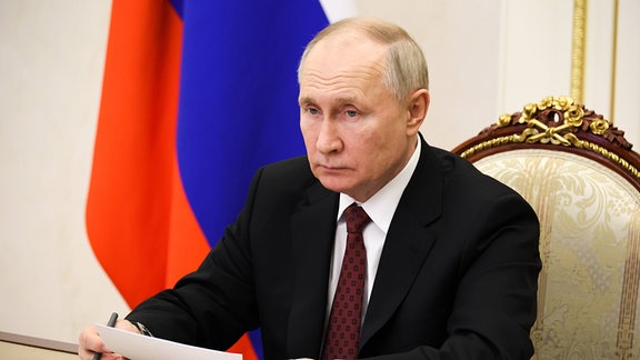 Putin sitzt an einem Schreibtisch