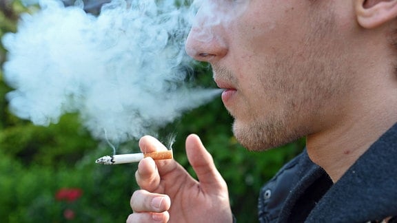 Ein junger Mann raucht eine Zigarette.