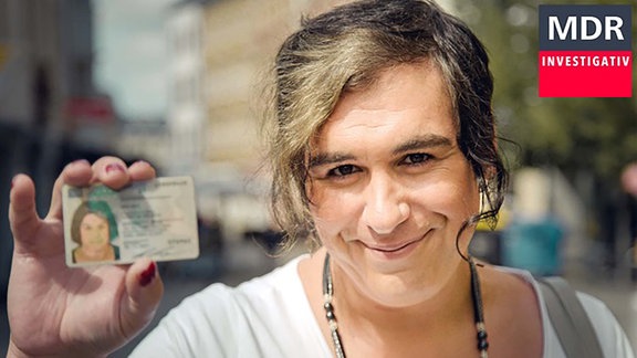 Eine Transfrau hält einen Personalausweis in die Kamera