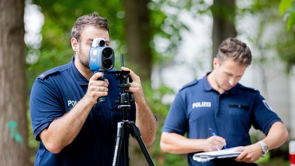 Zwei Polizisten kontrollieren mit Hilfe eines Lasermessgeräts die Geschwindigkeit des Autoverkehrs.
