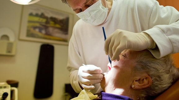 Ein Zahnarzt behandelt in seiner Praxis eine Frau