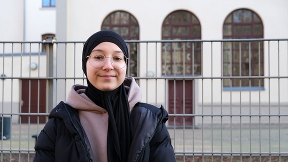 Aishat steht vor der Pestalozzi-Oberschule in Meißen