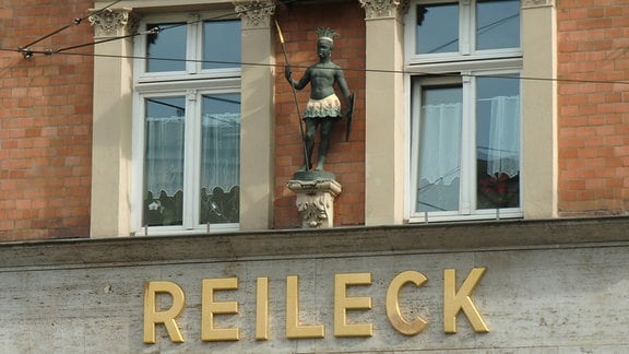 Eine männliche Skulptur an einer Hauswand der Mohrenapotheke in Halle
