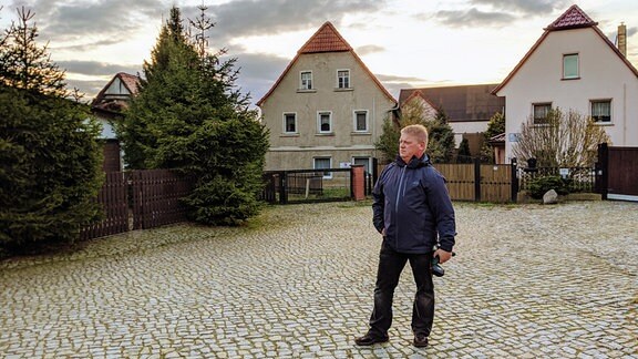 Ein Mann steht vor zwei Häusern in Pödelwitz.