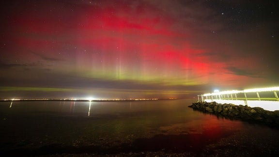 Polarlichter leuchten über der Lübecker Bucht,rechts im Bild ist die Seebrücke Niendorf zu sehen.