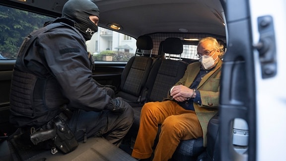 Bei einer Razzia gegen sogenannte «Reichsbürger» sitzt ein vermummter Polizist, nach der Durchsuchung eines Hauses, mit dem festgenommenen Heinrich XIII Prinz Reuß (r) in einem Polizeifahrzeug.