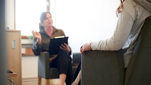 Eine Psychologin im Gespräch mit einen Patienten in einem Sessel.