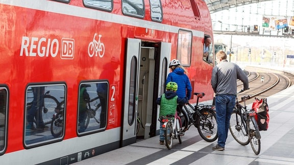 Eine Familie besteigt mit dem Fahrrad einen Regionalexpress der Deutschen Bahn.