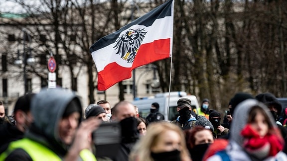 eilnehmer einer Demonstration von Rechtsextremisten und sogenannten Reichsbürgern laufen mit Reichskriegsflaggen die Straße