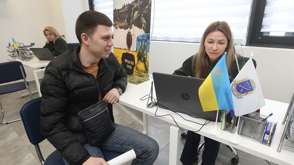 Ein Mann und eine Frau unterhalten sich bei der Eröffnung eines Rekrutierungszentrums für ukrainische Streitkräfte.
