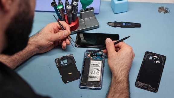 Ein Techniker arbeitet an einem Smartphone mit defektem Display