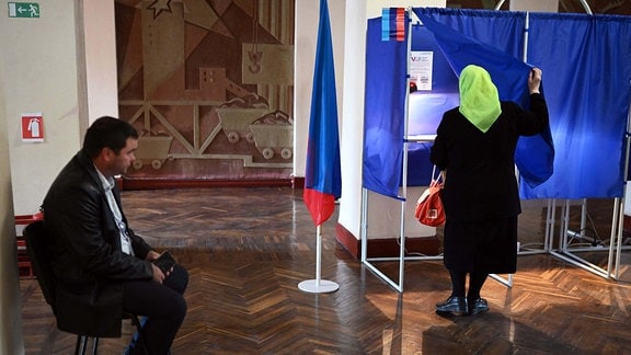 An elderly woman enters a voting booth at a polling station during regional elections in Krasnodon