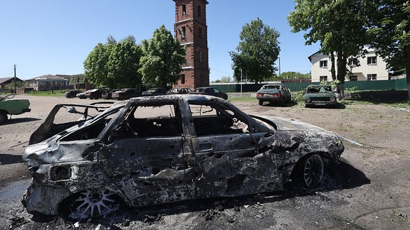 Nach einem russischen Angriff auf Solotschiw in der Region Charkiw im Nordosten der Ukraine ist ein ausgebranntes Auto auf der Straße zu sehen.