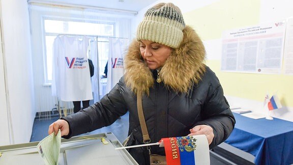 Eine Frau gibt während der russischen Präsidentschaftswahlen 2024 ihren Stimmzettel ab