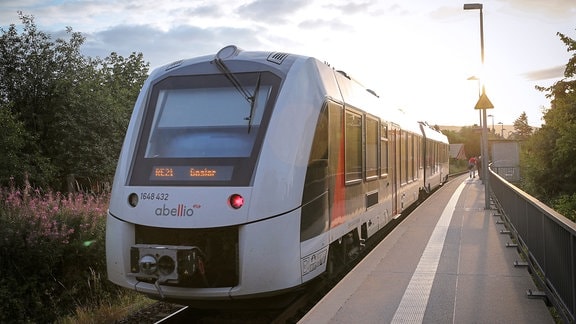 Bahnhof mit Zug am Bahnsteig im Sonnenuntergang