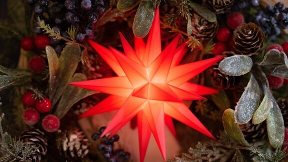 Ein Herrnhuter Stern aus Plastik leuchtet in der Schauwerkstatt der Herrnhuter Sterne GmbH. Der originale Herrnhuter Stern besteht aus 25 Zacken, davon 17 vier- und acht dreieckige.