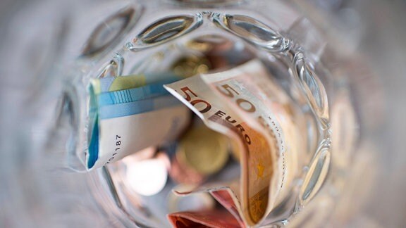 Geldscheine und Münzen in einem Glas.