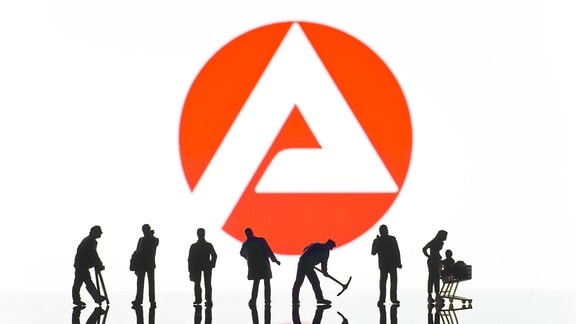 Figuren vor dem Logo der Arbeitsagentur