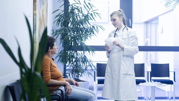 Eine Ärztin redet mt einer Patientin in einem Wartezimmer