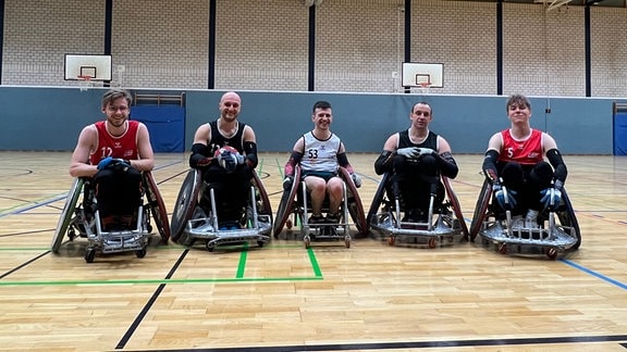 Fünf Rollstuhlfahrer in einer Sporthalle