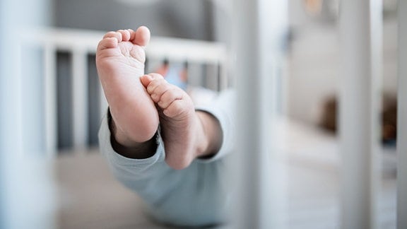 Die Füße eines Babys in einem Kinderbett