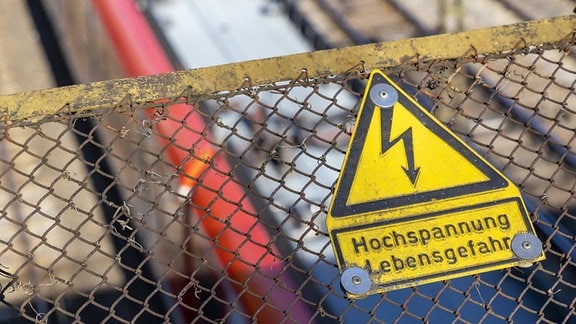 Schild 'Hochspannung Lebensgefahr' an einer Fußgängerbrücke über Bahngleisen